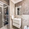 Bagno elegante con doccia in vetro, lavabo moderno e rivestimenti in pietra.