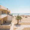 Una spiaggia con ombrelloni e sdraio, vista da un edificio con balconi.