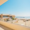 Vista da un balcone su una spiaggia con lettini e un edificio moderno.