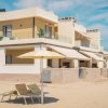 Un edificio moderno sulla spiaggia con ombrelloni e lettini.