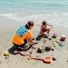 Due persone costruiscono un castello di sabbia sulla spiaggia.