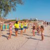Persone in spiaggia partecipano a un'attività di gruppo con bambini.