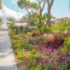 Un giardino fiorito con fiori colorati e alberi, immerso in un ambiente soleggiato.