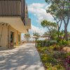 Terrazza di un edificio moderno con giardino fiorito e vista su ombrelloni da spiaggia.