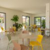 Sala interna con tavoli e sedie colorate, piante decorative.