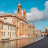 Edifici storici e canale con ponte e cielo parzialmente nuvoloso.