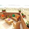 Terrazza con arredi e fiori affacciata su una spiaggia con ombrelloni.
