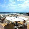 Area all'aperto con tavoli e ombrelloni su una spiaggia soleggiata.