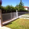 Giardino con erba e recinzione metallica, circondato da cespugli verdi.