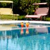Piscina con due cocktail colorati e sedie a sdraio rosse e gialle.