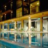 Piscina illuminata di notte con sedie a sdraio e palazzina a più piani sullo sfondo.