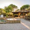 Edificio di pietra in un giardino con vialetti lastricati e piante rigogliose.