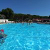 Persone nuotano in una piscina all'aperto con alberi sullo sfondo.