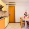 Cucina con mobili gialli e arancioni, tavolo in legno con fiori e porta di legno.