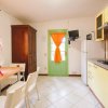 Cucina con porta verde, mobile alto in legno, tavolo con fiori e sedie bianche.