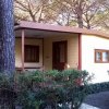 Una casetta di legno in un'area boschiva con ampio portico e finestre.