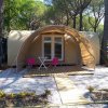 Tenda moderna con terrazza in legno e sedie davanti, circondata da alberi.