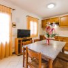Cucina accogliente con tavolo in pietra, TV e mobili in legno chiaro.