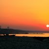 Spiaggia al tramonto con una torretta di salvataggio e bandiere.