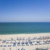 Spiaggia sabbiosa con ombrelloni blu e bianchi.