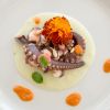 Polpo con crema bianca e decorazione di fiori e salse.