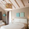 Camera da letto luminosa con soffitto a travi e arredi chiari.