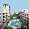 Complesso residenziale con piscina centrale, circondato da edifici e alberi sullo sfondo.