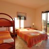 Camera con letto matrimoniale e letto a castello, porta finestra aperta su balcone.