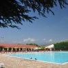 Ampia piscina all'aperto con lettini e tettoie circostanti.