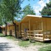 Alcuni bungalow di legno lungo un viale alberato con sedie sul patio.