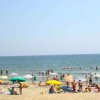 Spiaggia affollata con bagnanti e ombrelloni colorati davanti al mare.