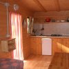 Interno di una casetta in legno con cucina compatta, frigorifero e tavolo.