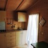 Cucina in legno chiaro con mobili, fornelli e tende bianche.