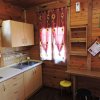 Cucina in legno con pensili beige, lavello, fornelli e sgabelli colorati. Finestra con tende rosse.