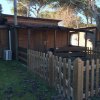 Piccola casa di legno recintata con alberi intorno, porta marrone e aria condizionata esterna.