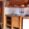 Piccola cucina in legno con lavello, piano cottura, e frigorifero.