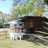 Bungalow in legno con terrazza, tavolo, sedie e ombrellone nel giardino.