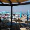 Vista dalla terrazza di un bar sulla spiaggia con ombrelloni e lettini blu.