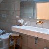 Bagno moderno con lavabo bianco, bidet e WC, pareti piastrellate color beige.