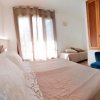 Stanza luminosa con letto, divano blu, mobili e TV a parete.