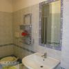 Un bagno con lavabo bianco, specchio rettangolare e piastrelle con bordi blu.