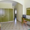 Una stanza d'albergo con armadio verde, scrivania con specchio, sedia e TV.