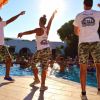 Tre animatori intrattengono vicino a una piscina soleggiata.