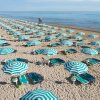 Spiaggia con ombrelloni a strisce verde e bianco.