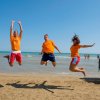 Tre persone saltano sorridenti sulla spiaggia.