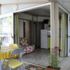 Patio con tavolo giallo, cucina aperta e piante fiorite.