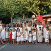 Gruppo di persone in costumi antichi davanti a un chiosco, circondati da alberi.