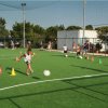 Bambino calcia un pallone in un campo da gioco all'aperto.