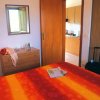 Camera con letto colorato, cassettone e vista su cucina.