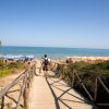 Un sentiero di legno conduce a una spiaggia con ombrelloni, vista sul mare.